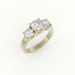 Gouden verlovingsring met rond afgewerkte band en drie diamanten.