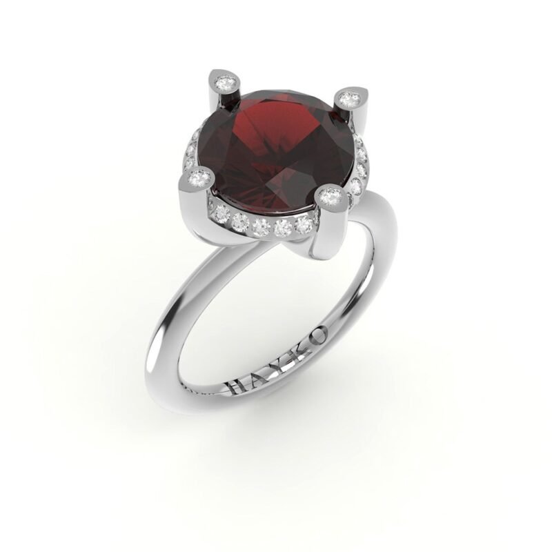Witgouden solitaire ring met robijn omringd door diamanten.
